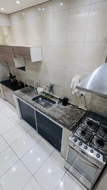 Cozinha com pia de granito, fogão e coifa