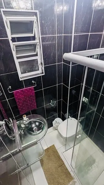 Banheiro com revestimento escuro e box de vidro