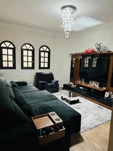Sala com sofá, estante com TV e lustre de cristal