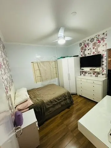 Suíte com cama de casal, armário branco e papel de parede floral