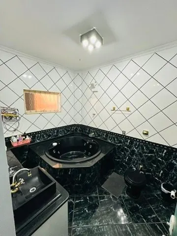 Banheiro da suíte com banheira de hidromassagem e revestimento preto