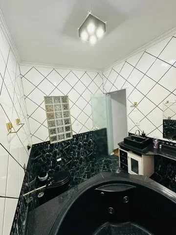 Banheiro com banheira de hidromassagem e janela de blocos de vidro