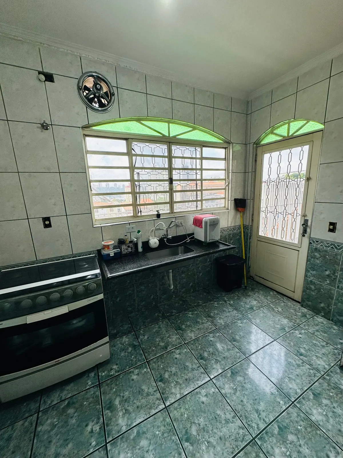 Cozinha com fogão, pia e porta para a área externa